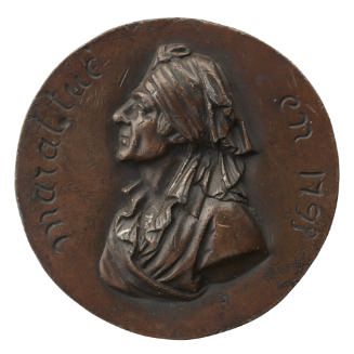 Bronze medal of a man in profile to the left wearing a robe and towel around his head
