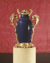 Blue porcelain and gilt bronze mounted vase on a pedestal against a red background