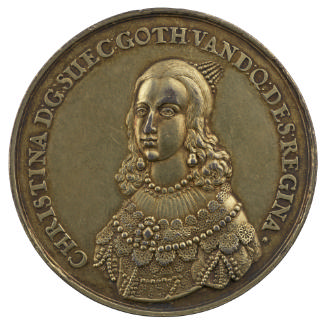 Silver medal of a woman with long hair, wearing earrings, a pearl necklace, and a dress with he…