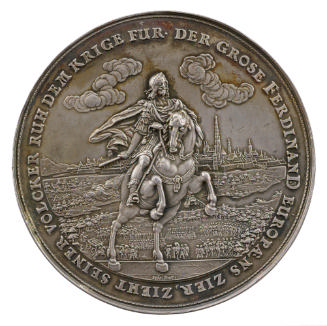 Silver medal depicting a man on a rearing steed in front of troops and a walled cityscape