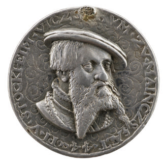 Silver medal of man with a beard wearing a hat