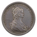 Silver medal of a woman in profile to the right, wearing a gown tied in the front with a sash