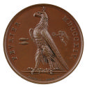 Bronze medal of an eagle in profile with two small fish to its left and a nude, winged victory …