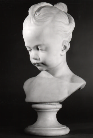 Marble bust of a young girl.  Her head and eyes are tilted downward, she has her hair twisted i…
