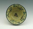 View of interior of porcelain bowl with flaring ring and black ground with vegetal designs