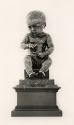 Bronze sculpture of a seated child.
