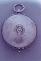 Image of reverse side of watch with a stylized floral motif in the center