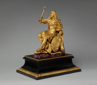 Golden sculpture of a seated Louis XIV, he is holding a raised scepter in his right hand and a …