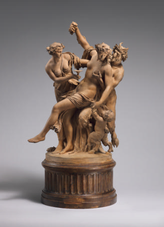 Terracotta sculpture of a Satyr with two Bacchantes.  The satyr stands behind one of the nude B…