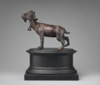 Bronze sculpture of a goat, a collar with a bell are around its neck.