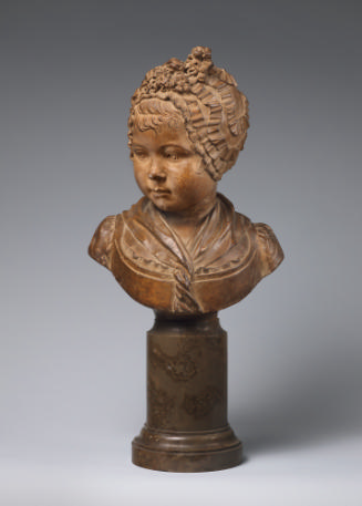 Terracotta bust of a young girl.  She wears a bonnet with ribbons and flowers, she is looking d…