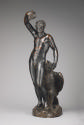 A bronze sculpture of Ganymede.  His head is pointed down, he looks at an eagle that is by his …