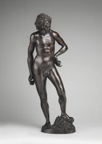 A bronze sculpture of David. He is looking down, his left hand is on his left hip and his left …