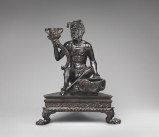 A bronze sculpture of a seated satyr with inkstand to his left and a candlestick holder held up…