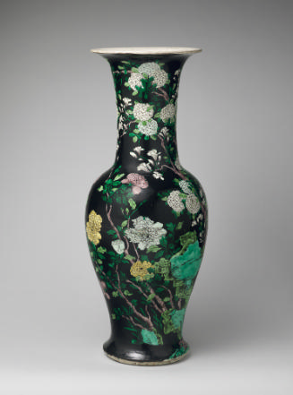 Black ground porcelain vase with branches, leaves, rocks, and yellow and white flowers