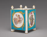 Porcelain cubical dish in blue, white, and gold with cupids and trophies
