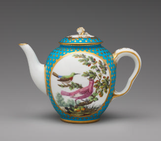 Porcelain teapot in white, blue, and gold with image of birds in a tree