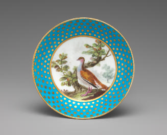 Porcelain saucer in blue and gold with image of bird near tree