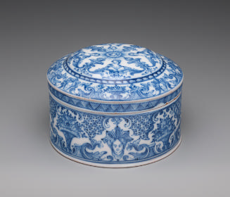 Circular, covered powder box with blue scrollwork decoration