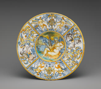 Circular plate with central scene showing a man in a landscape, surrounded by a border of ornat…