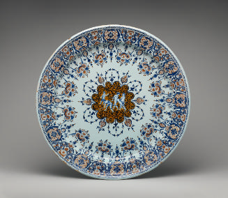 Large circular plate with putti in the middle surrounded by ornate decoration in red and blue