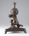 Bronze sculpture of crouching Atlas supporting globe with triangular base; side view