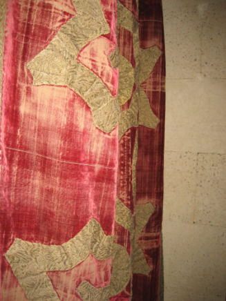 Red velvet hanging with woven design against stone background
