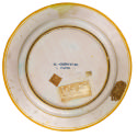 Reverse side of dish, plain white, with four labels and an inscription in the middle