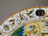Detail of top left corner of plate showing thick white border decorated with arabesques, sphing…