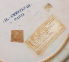 Detail of reverse side of dish, plain white with three labels and a blue inscription