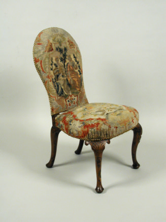 Chair with needlepoint upholstery showing two women seated outside holding vines and grapes, wi…