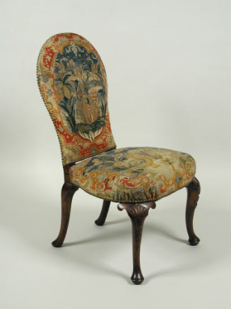 Chair with needlepoint upholstery showing woman seated outside, birds, flowers, and vegetal dec…
