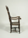 Side view of walnut armchair with scrollwork decoration and woven seat