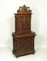 Walnut and pine cabinet with relief carving of masks and vegetal motifs