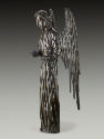 A bronze sculpture of an angel.  The angel stands upright with wings stretched behind it, the r…