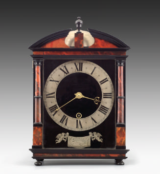 Front view of Hague Clock with silver dial set against an architectural case made of veneered t…