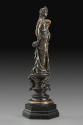 Side view of a bronze sculpture of a female figure with a cornucopia.  Her head is turned to he…
