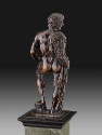 Back view of a bronze sculpture of Hercules.  His head is turned to his right and he has a lion…