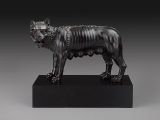 Bronze sculpture of a she-wolf.  Her head is turned to the left.