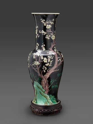 Tall porcelain vase with black ground with designs of trees and mountains