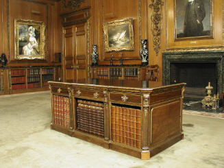 Walnut table with drawers and gilded ornaments, holding books