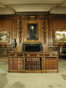 Front view of walnut table with drawers and gilded ornaments, holding books