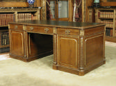Front view of leather-topped walnut desk with gilded ornaments