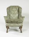 Front view of winged armchair upholstered in light green silk with a damasque motif