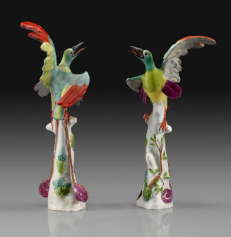 A pair of two birds of paradise in porcelain perched on trunks decorated with vegetal motifs 