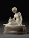 Marble sculpture of Friendship.  She is sitting down with her legs stretched out to her right s…