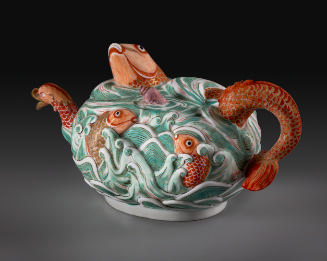 Three-quarter view of porcelain teapot depicting high relief fish in water in orange and green …