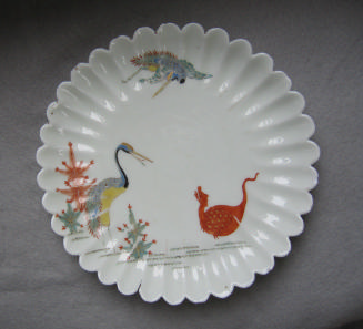Fluted dish in white porcelain showing two herons and a dragon in various colors of glaze