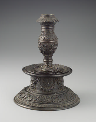 Bronze candlestick featuring intricate motifs throughout.