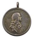 Silver medal of a king in armor and a broad collar, wearing drapery tied in a knot at the shoul…